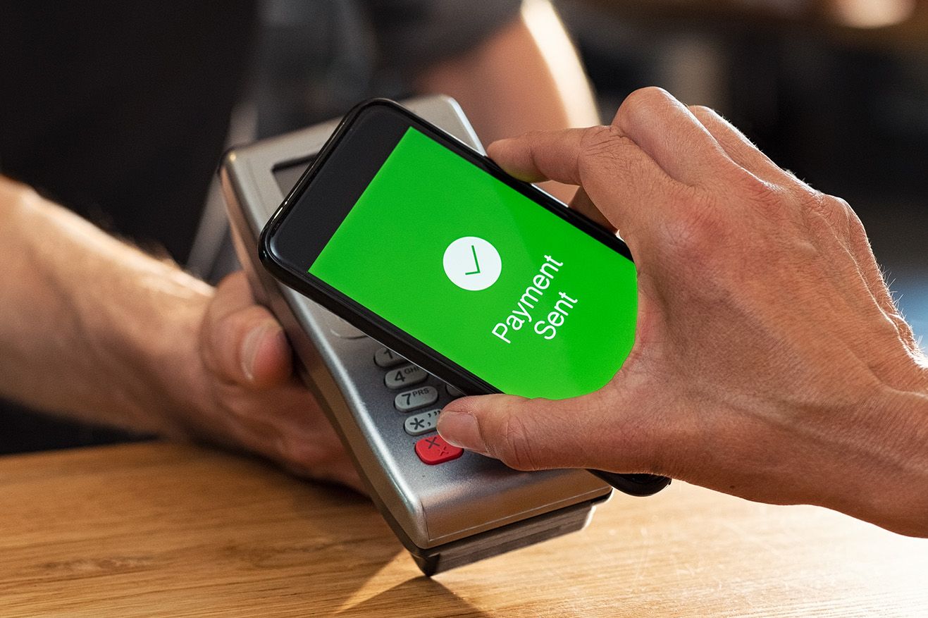 Retail Customer Making Payment at Checkout Via Mobile Device